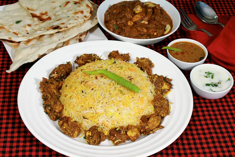 A plate of Sindhi Biryani garnished with fresh herbs and paired with yogurt.