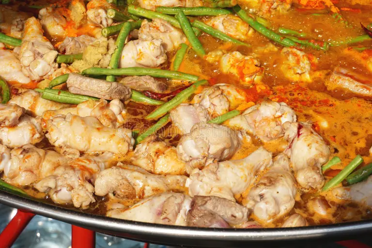 A mid-cooking shot of a steaming pot of Chicken Karahi with visible spices.