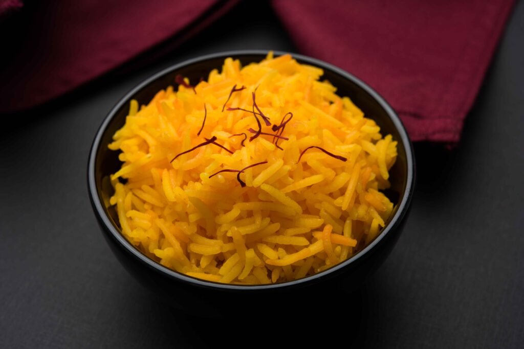A beautifully plated bowl of Basmati rice with saffron and garnished with nuts, showcasing its fluffy texture.